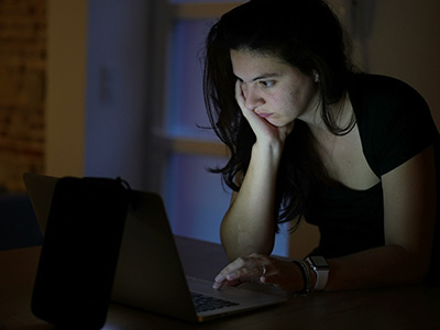 Woman browsing internet in front of laptop screen at night