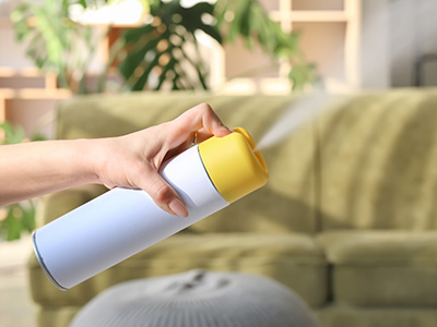 Woman spraying air freshener at home