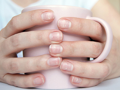 Close-up of female hands with a lot of white dots on nails, holding mug