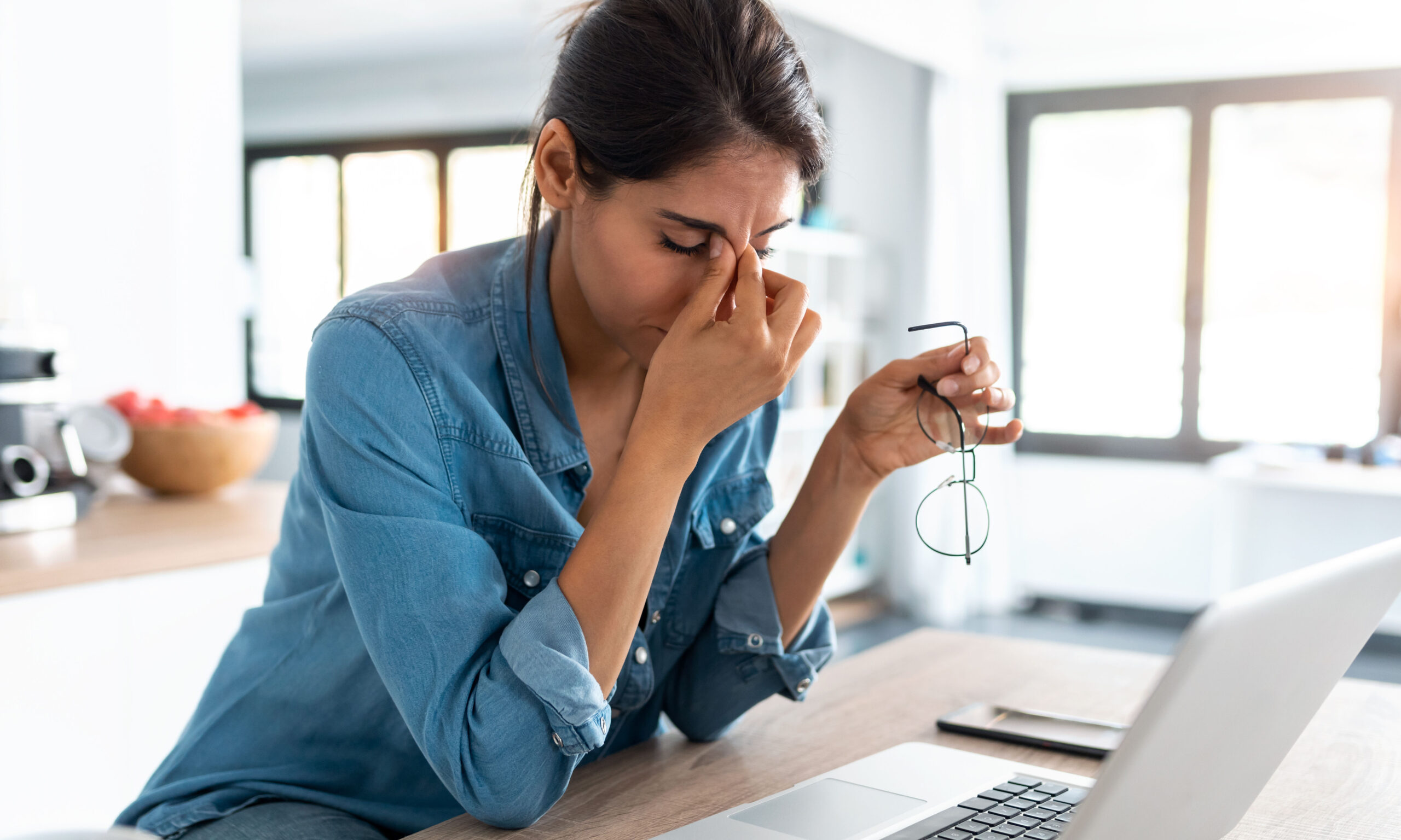 Shot of stressed business woman working from home on laptop looking worried, tired and overwhelmed.