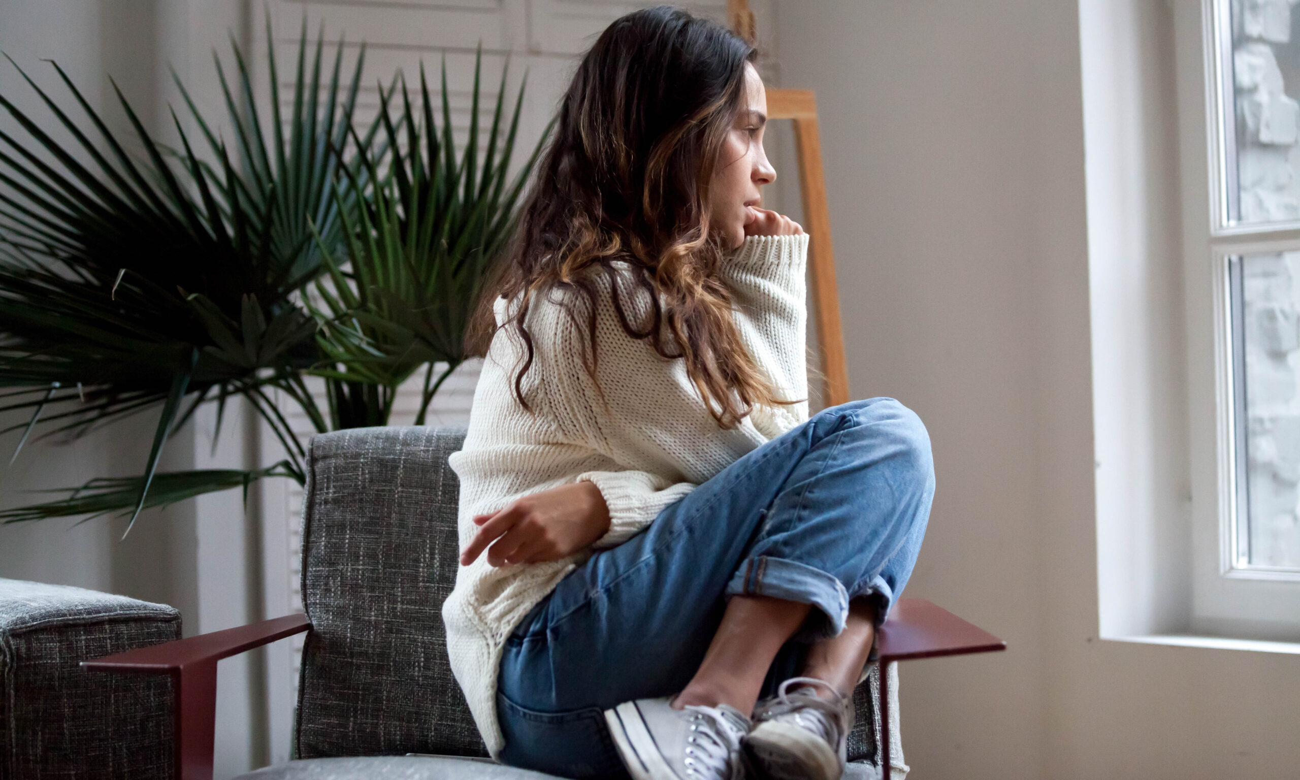Sad thoughtful teen girl sits on chair feels depressed, offended or lonely, upset young woman suffers from abuse, harassment or heartbreak, grieving lady or violence victim has psychological problem