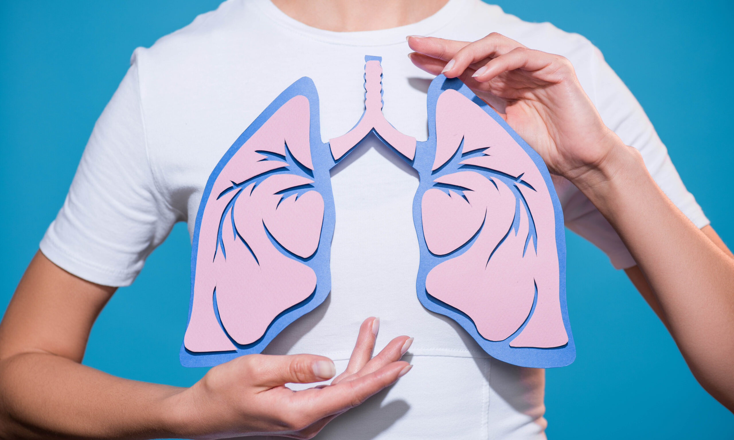 partial view of woman in white tshirt with paper crafted lungs on blue backdrop
