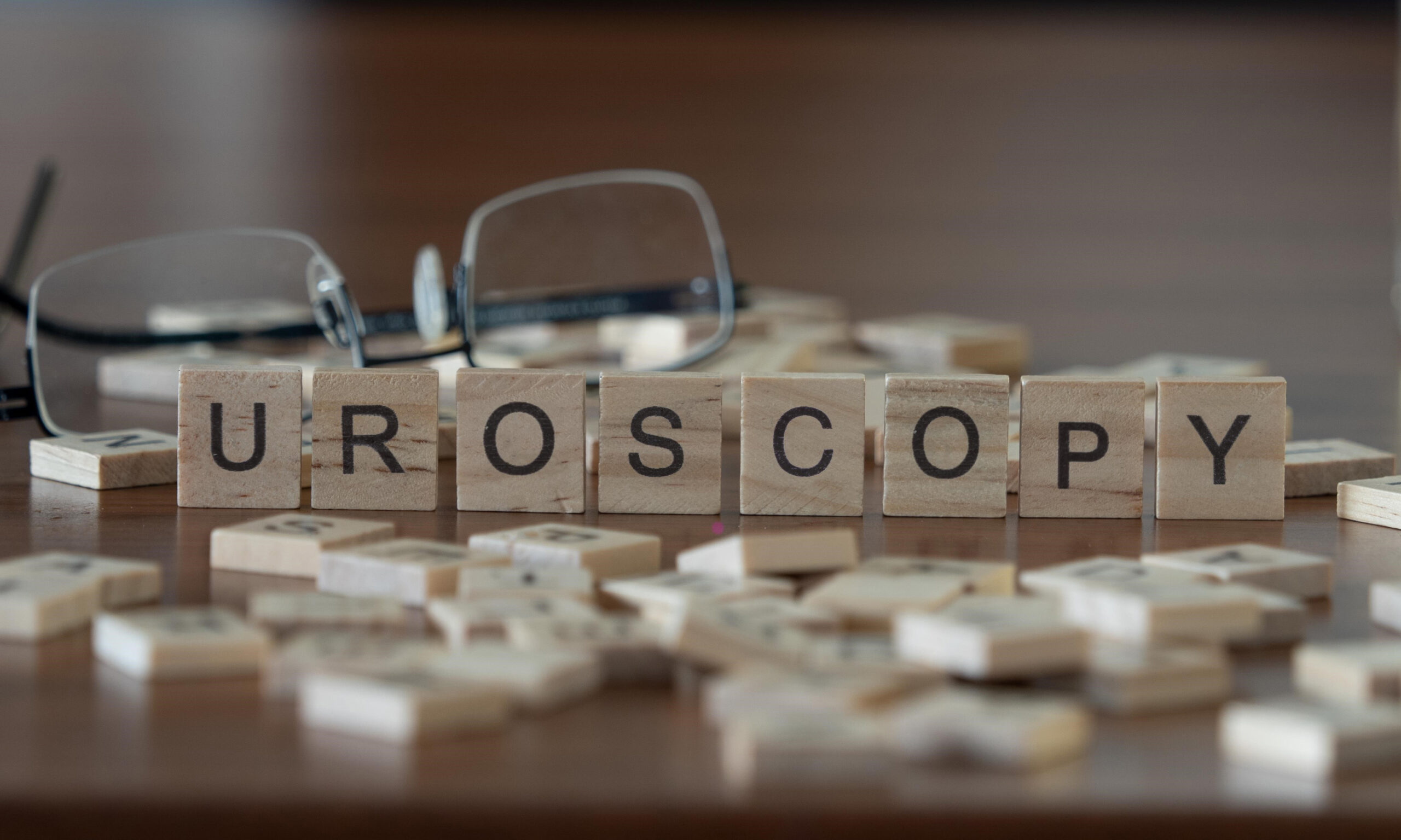 uroscopy word or concept represented by wooden letter tiles on a wooden table with glasses and a book