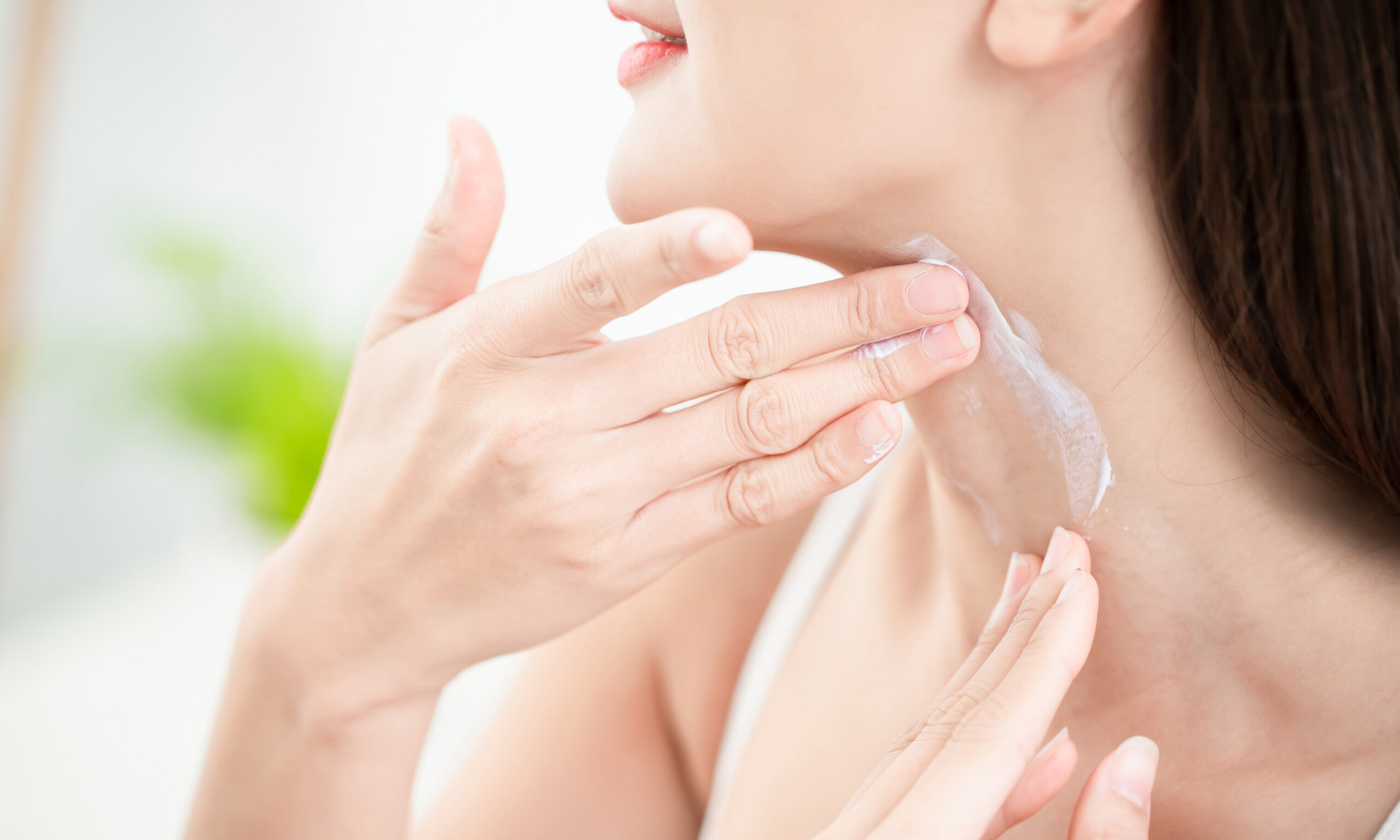 young beauty woman applying cream or sunscreen on her neck
