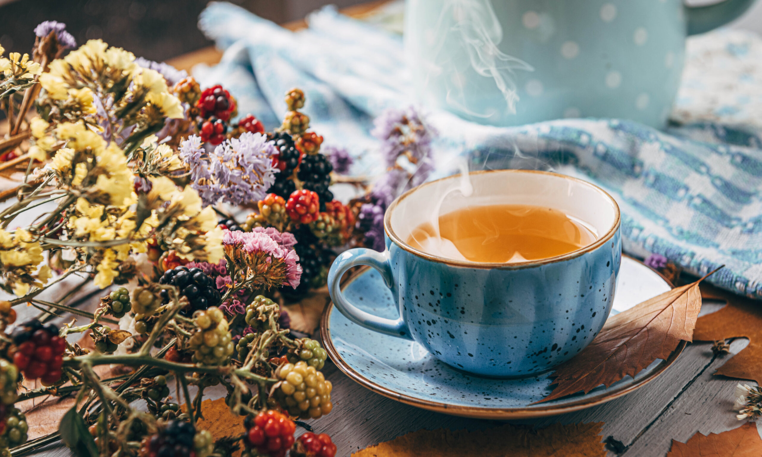 autumn warming tea on a wooden table with autumn tree leaves lying nearby