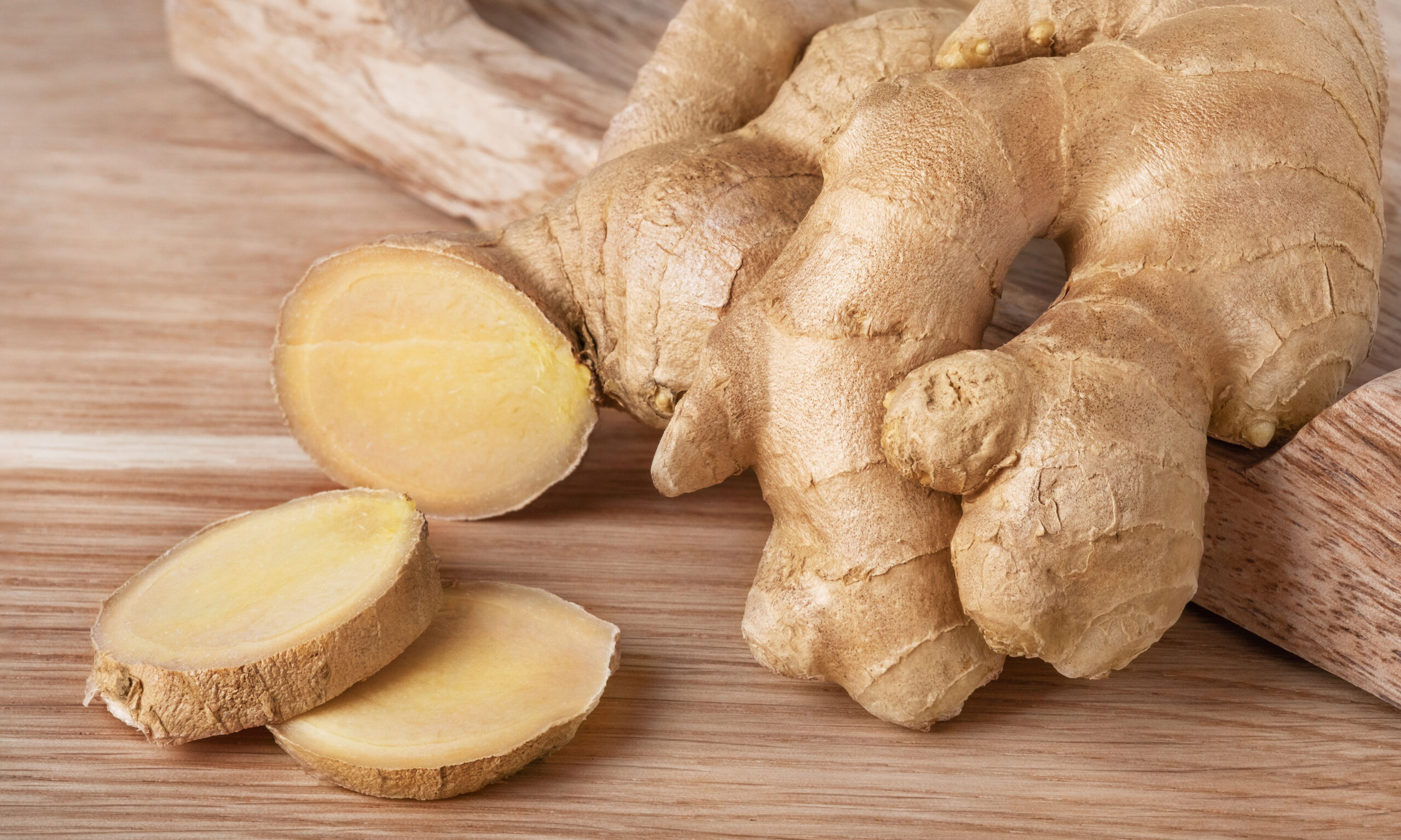 Fresh ginger root whole and slices on wood background. Natural spice or ingredient for herbal medicine.