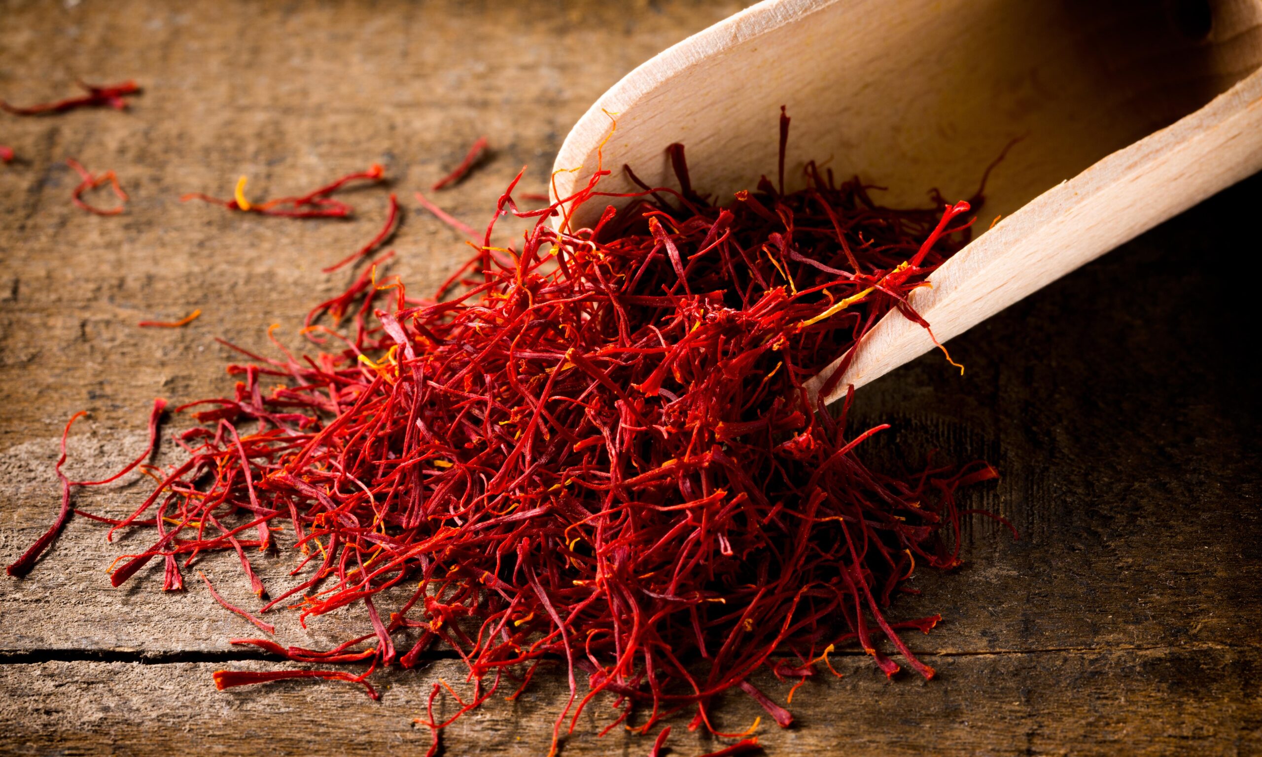 saffron threads with spice shovel on wooden background, closeup,