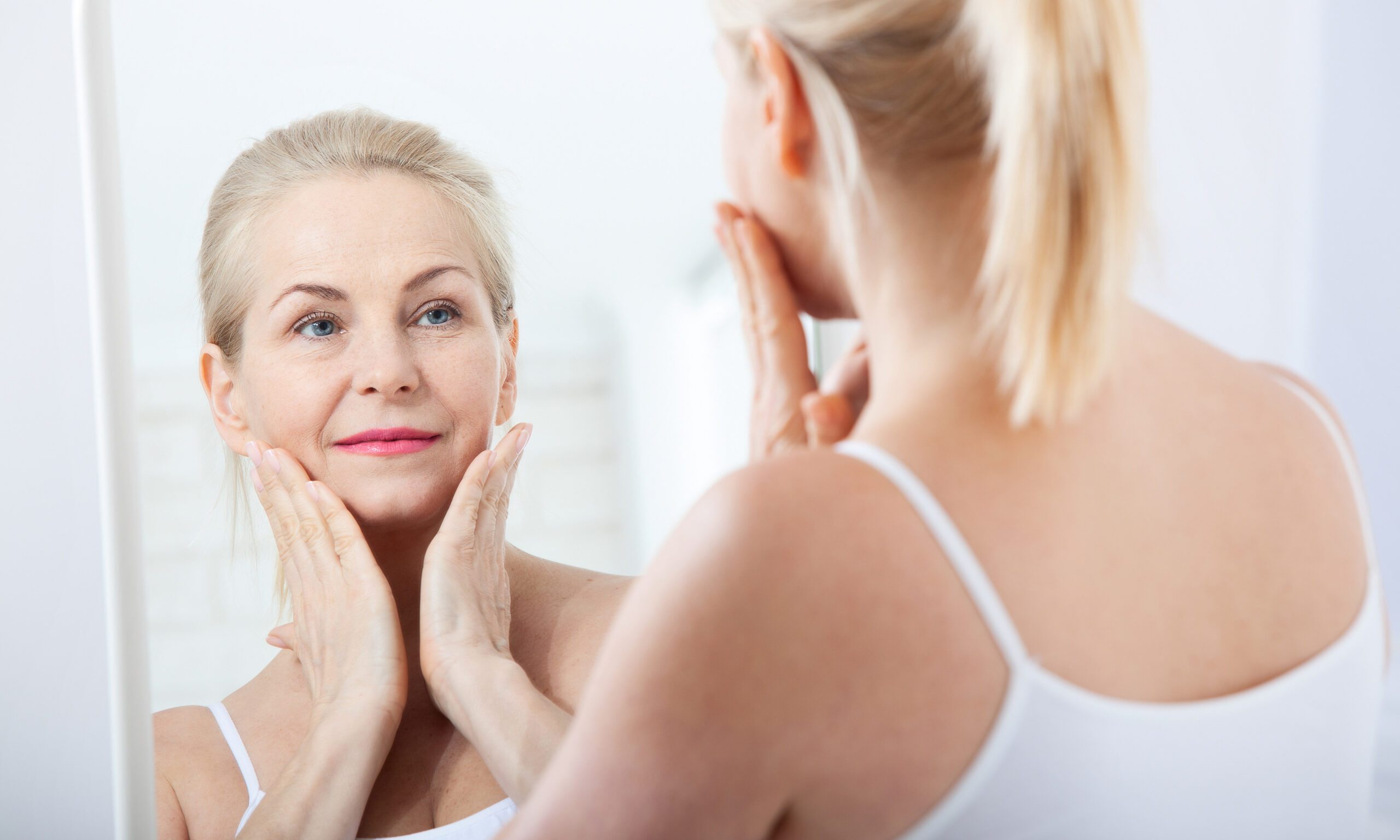 Middle aged woman looking at wrinkles in mirror. Plastic surgery and collagen injections. Makeup. Macro face. Selective focus on the face. Realistic images with their own imperfections.