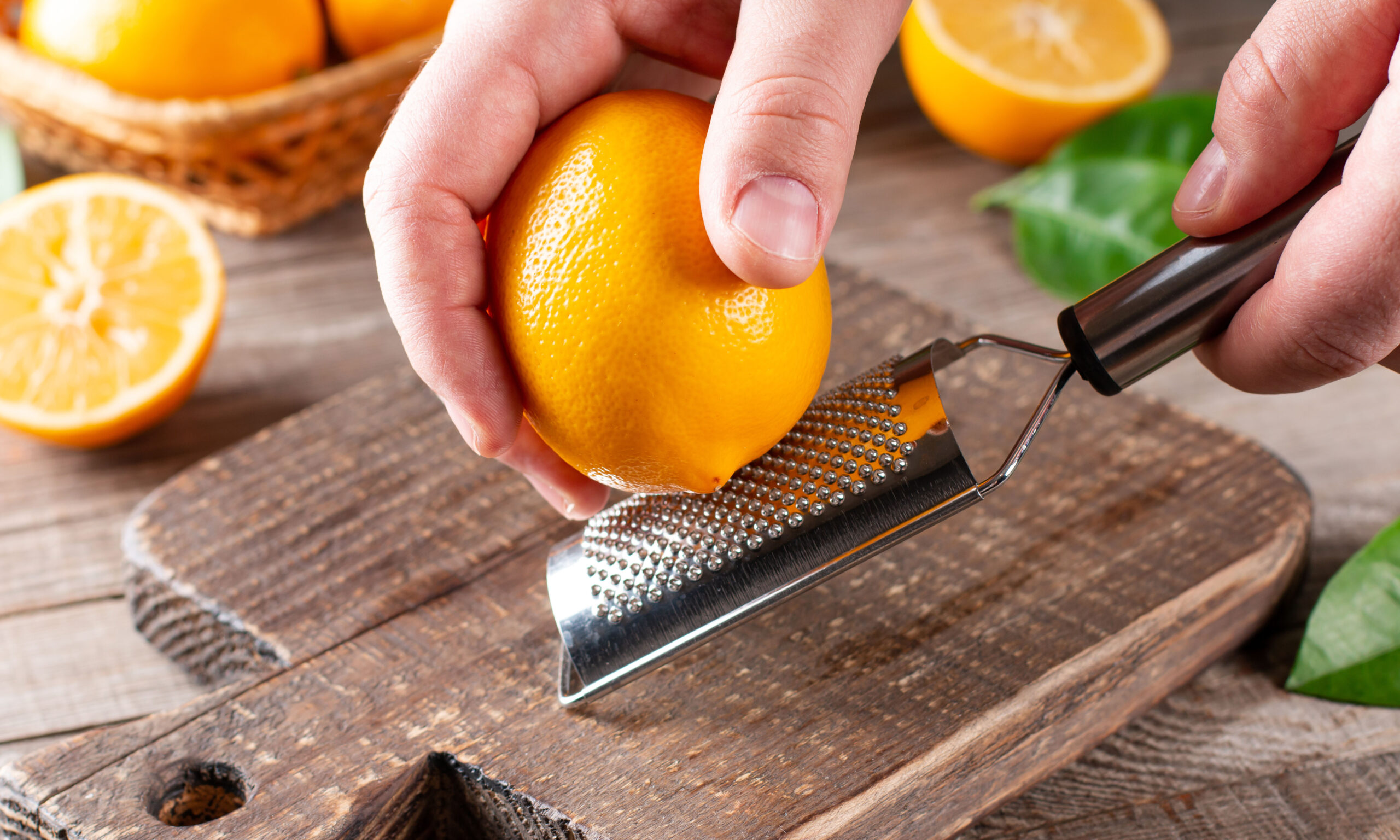 Man taking off lemon peel with zester over table