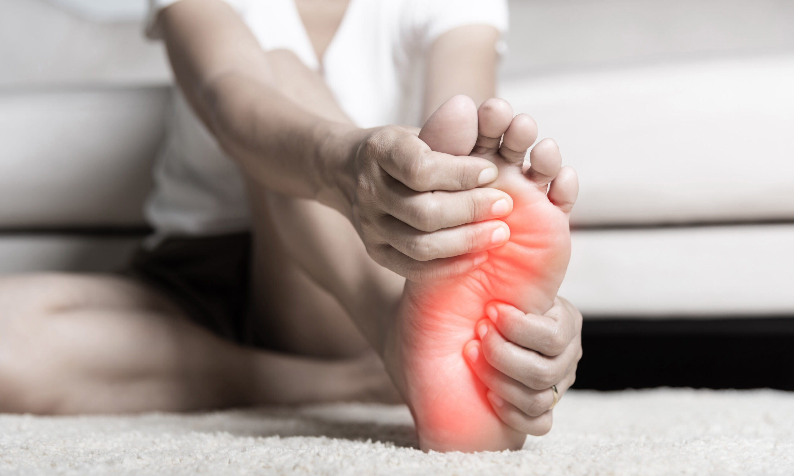 Foot pain, Asian woman feeling pain in her foot at home, female suffering from feet ache use hand massage relax muscle from soles in home interior, Healthcare problems and podiatry medical concept