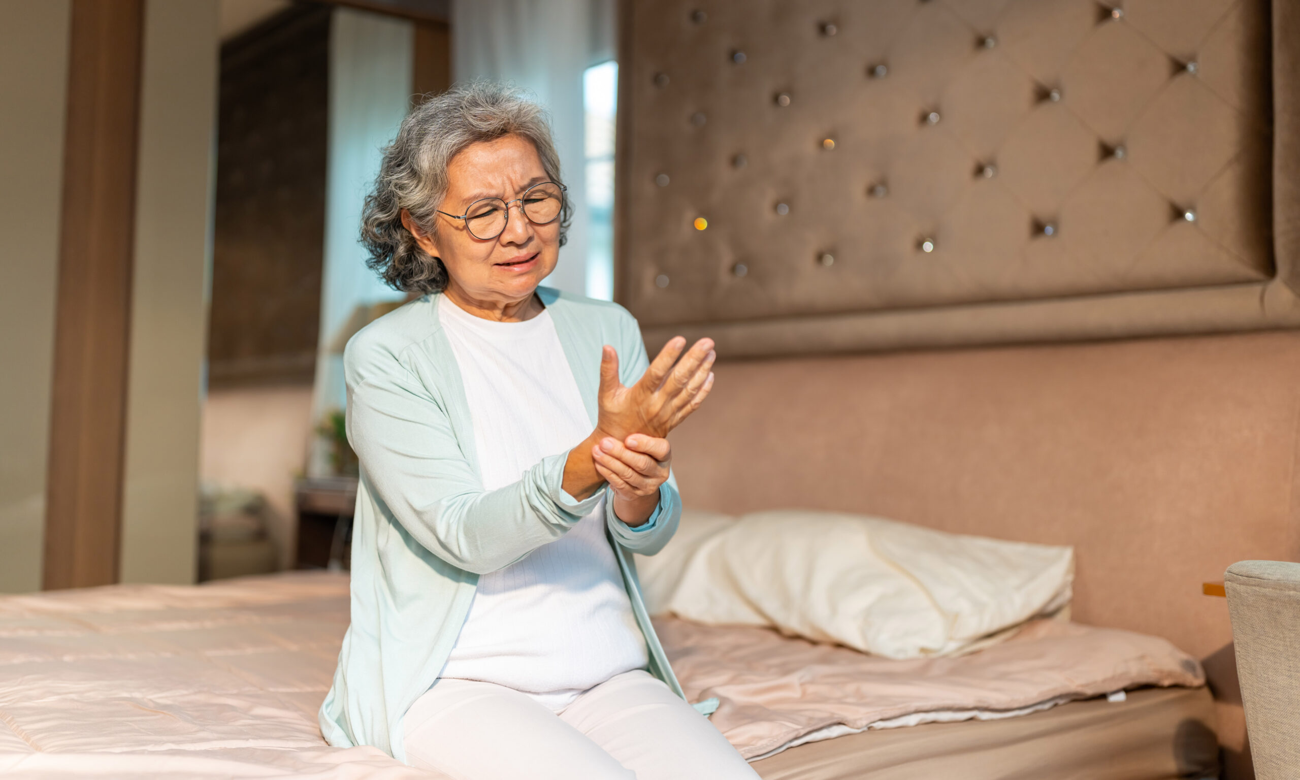Asian senior woman massaging hand, suffering from finger wrist h