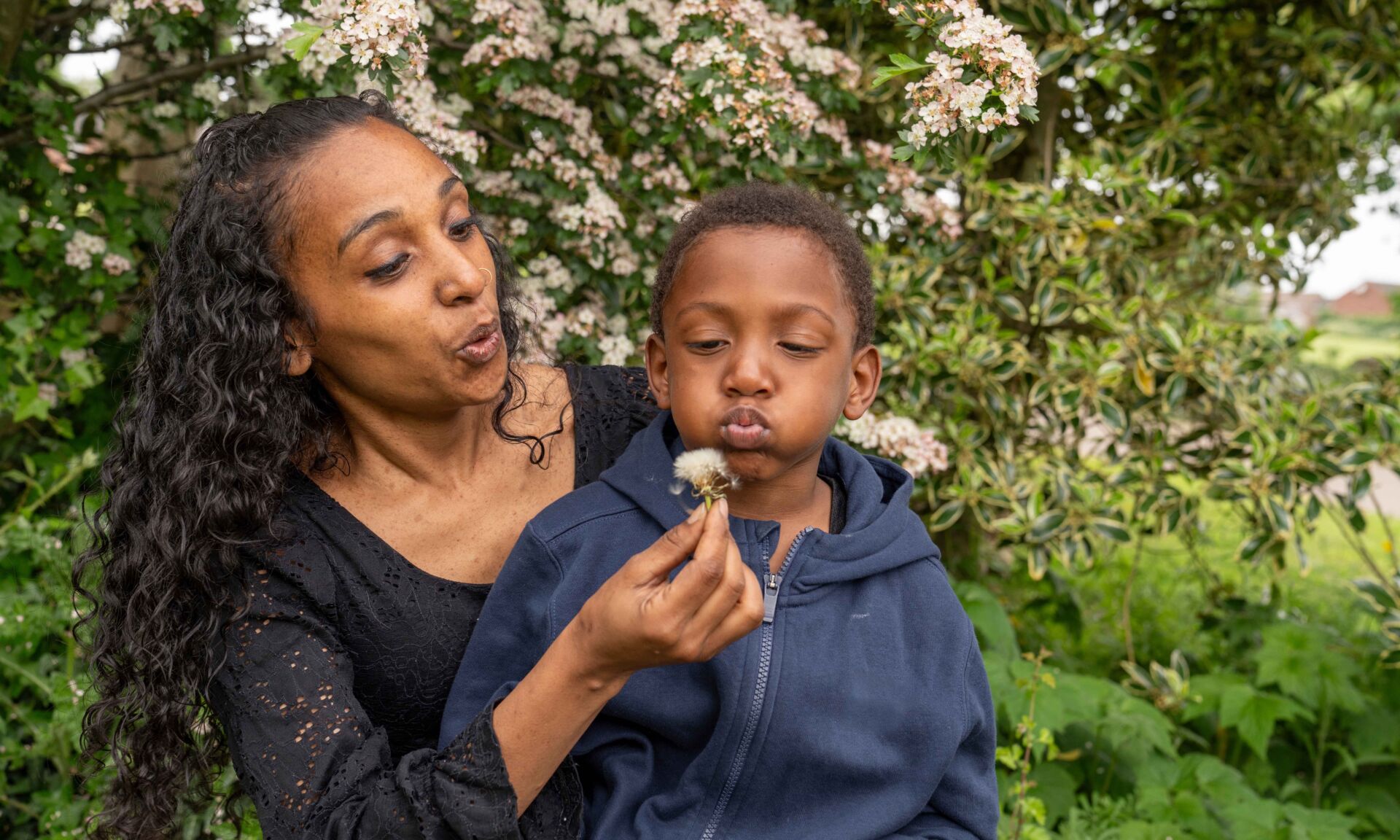 Mother and son blowing dandelion flower