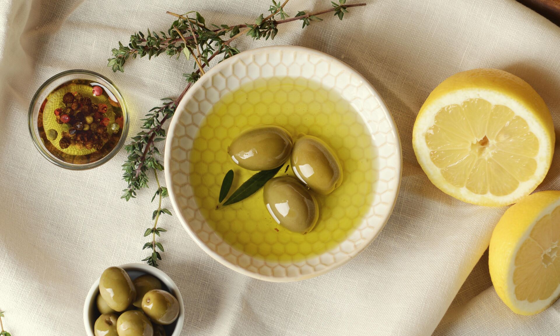 Tasty olive oil with lemon and herbs on table, top view