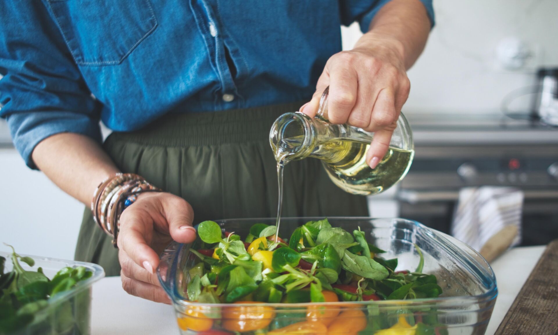 Woman Adding Olive Oil In Vegetable Salad