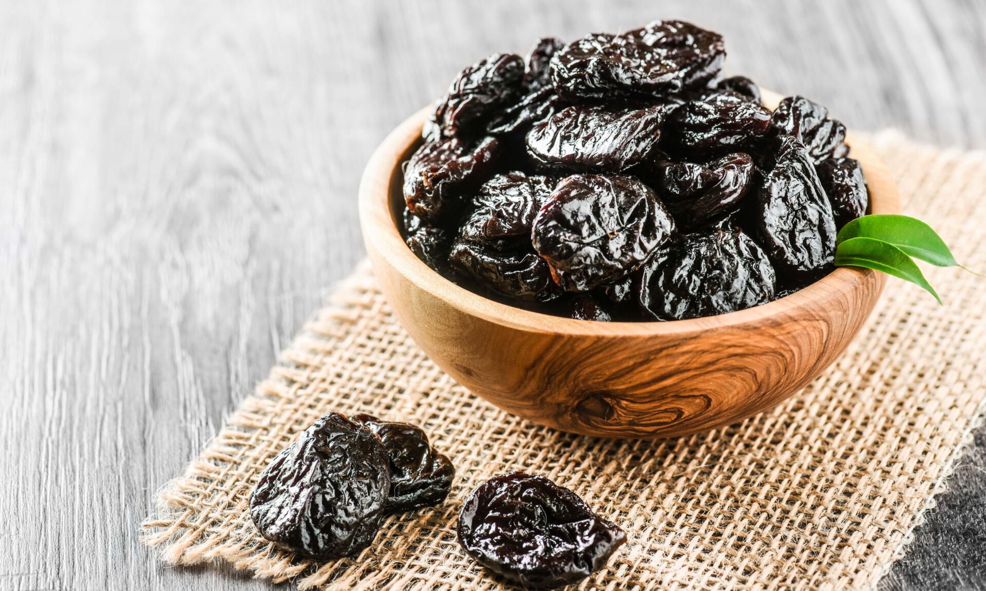 Fresh prunes in wooden bowl. Prunes on stone dark table. Prunes healthy food. Dried plums.