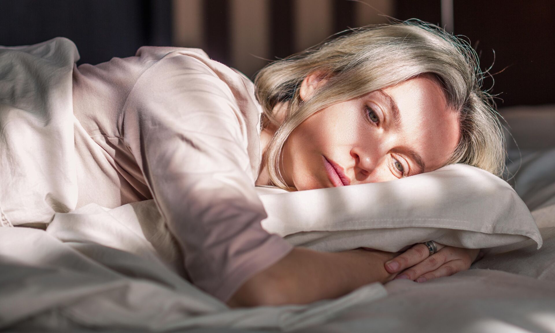 Stressed middle aged woman lying on bet at home and crying. Unhappy woman suffering from nervous tension, emotional disorders, psychological problems, breakup. Frustrated female feeling lonely and offended