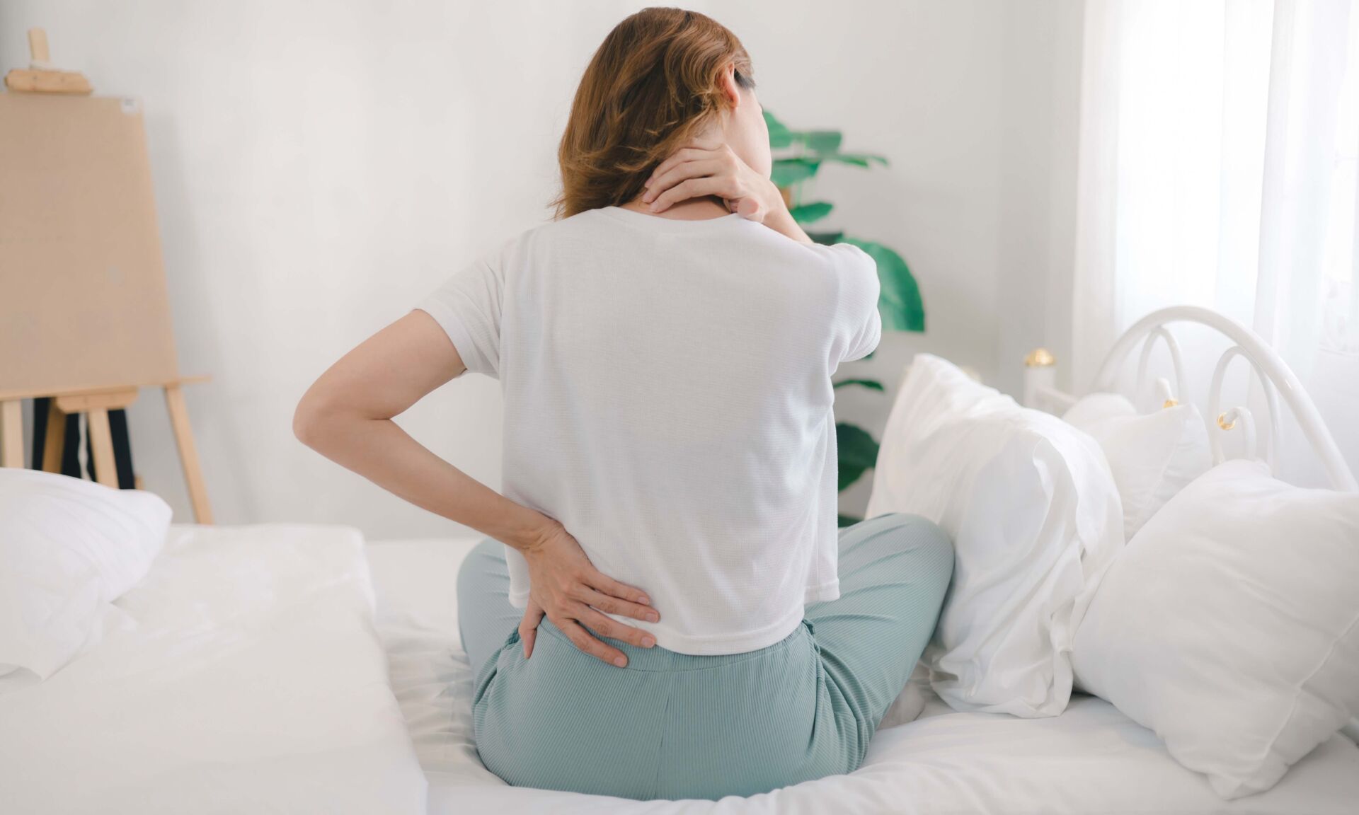 The young woman experienced body aches while sitting on the bed.