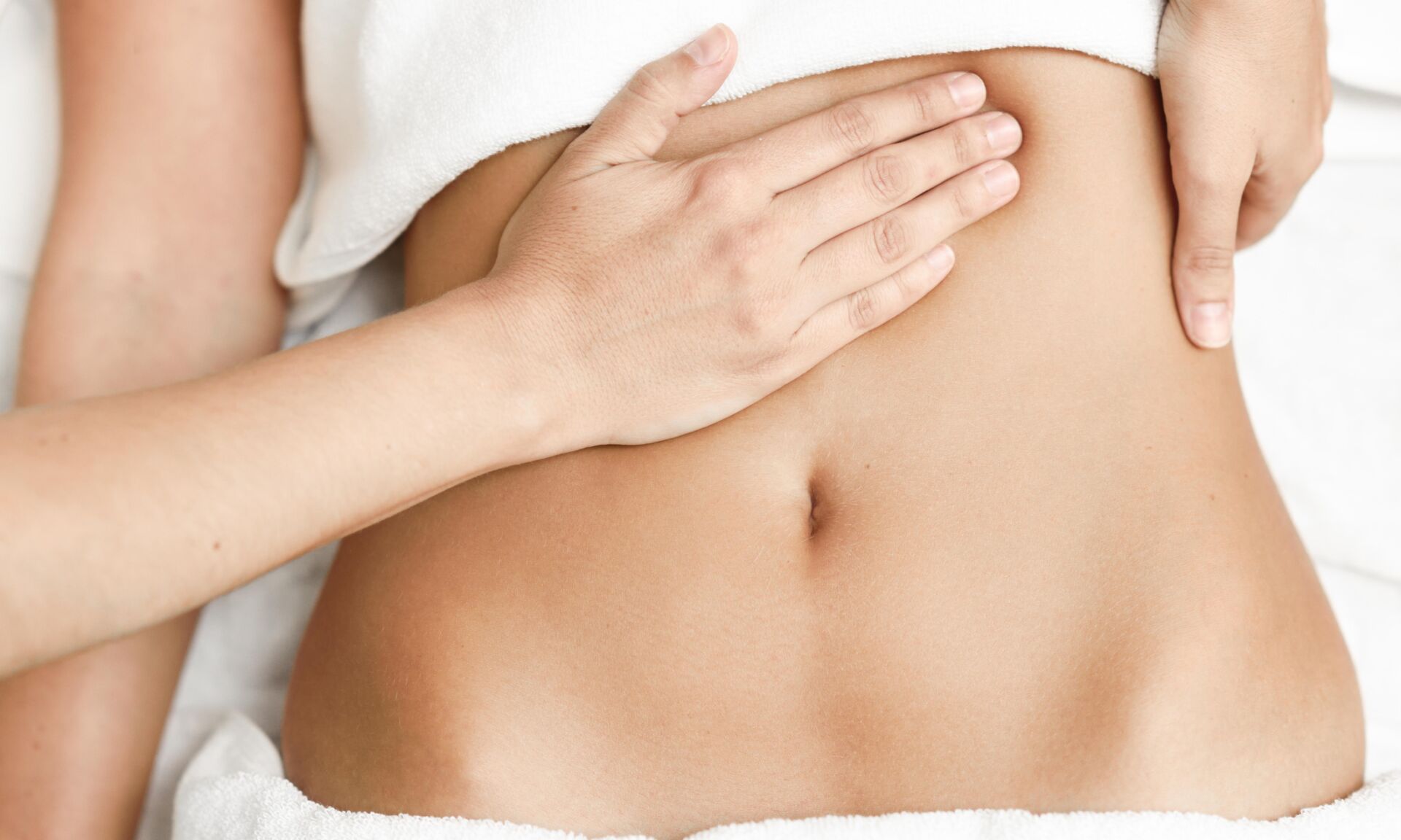 Top view of hands massaging female abdomen.Therapist applying pressure on belly. Woman receiving massage at spa salon