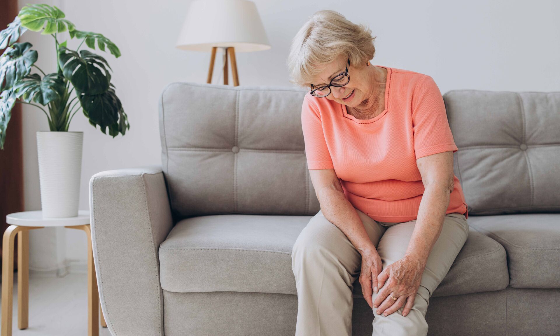 Senior woman suffering from pain in knee at home