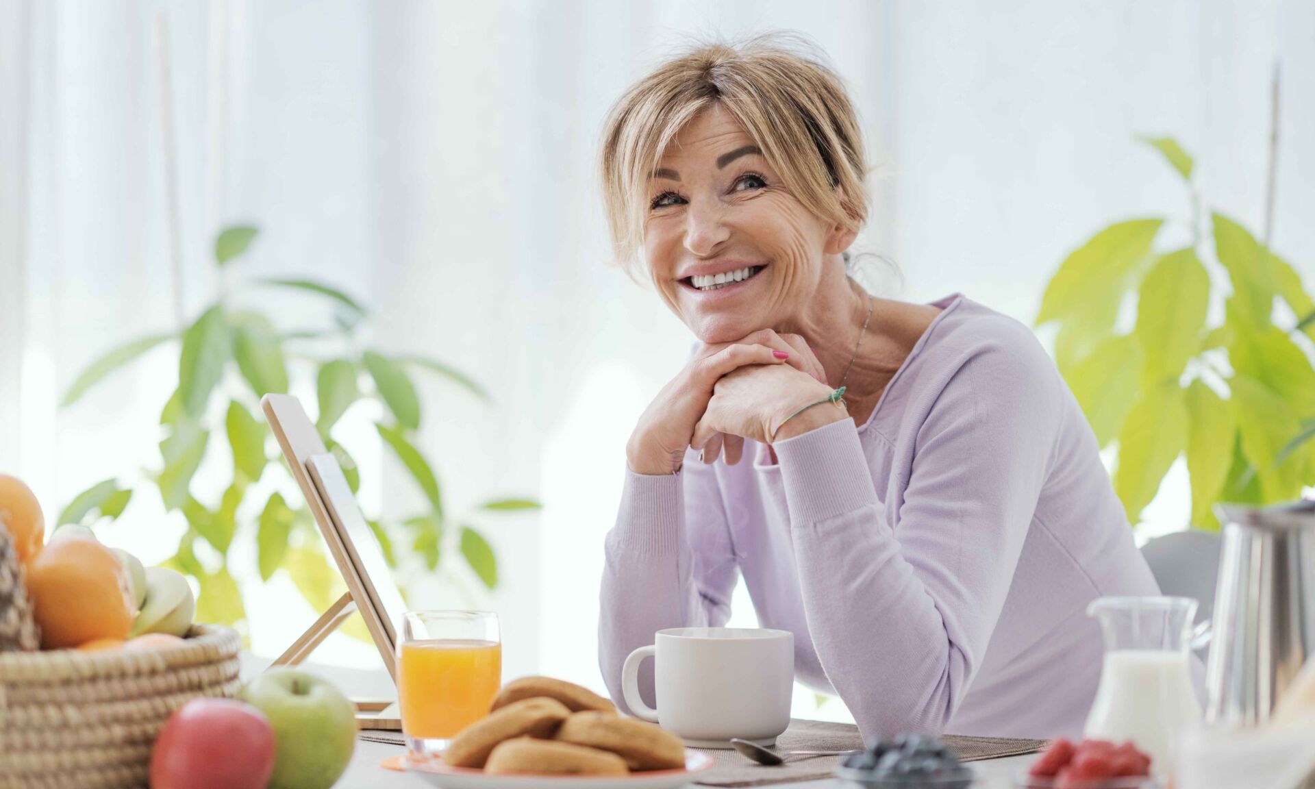 Beautiful mature woman having a relaxing breakfast at home, she is smiling at camera
