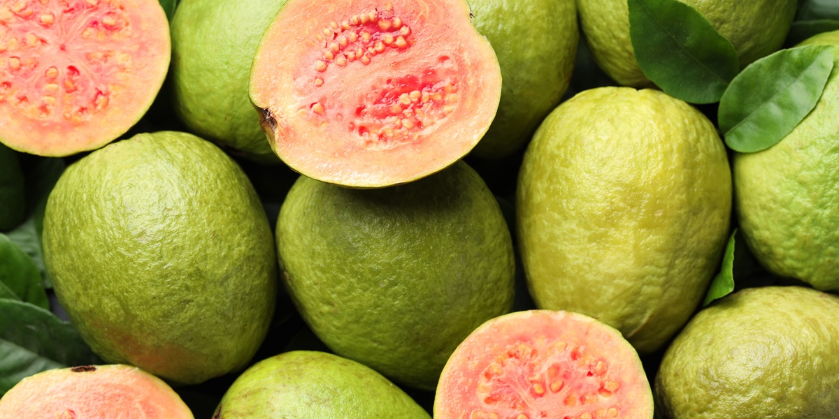 Fresh cut and whole guava fruits as background, top view